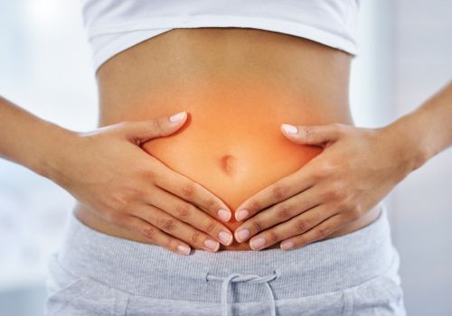 Gut Health during Menopause: 9 Essential Tips Woman in her 40s gently holding her stomach in soft morning light to represent gut health during menopause